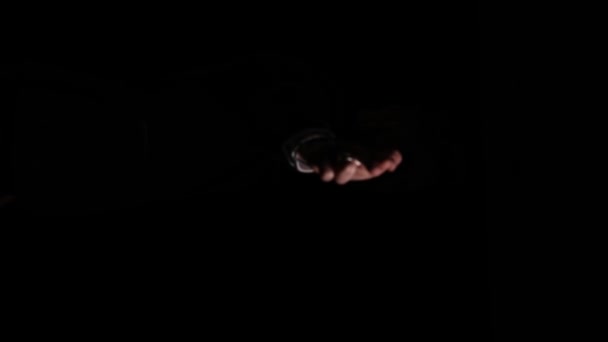 misterioso giovane uomo che fa un gesto di pistola dal buio, tenendo le dita in bocca ed espirando fumo, scomparendo al buio su sfondo nero in studio - Filmati, video