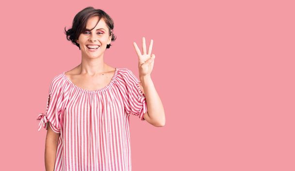 Beautiful young woman with short hair wearing casual summer clothes showing and pointing up with fingers number three while smiling confident and happy.  - Фото, изображение