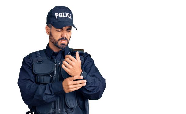 Jeune homme hispanique portant uniforme de police souffrant de douleur aux mains et aux doigts, inflammation de l'arthrite  - Photo, image