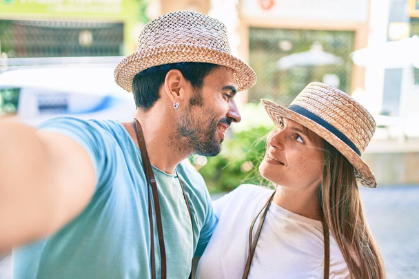 Fiatal pár barát és barátnő turisták egy nyári utazás visel nyári kalap csinál egy szelfi kép - Fotó, kép