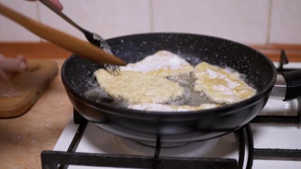 Weibliche Hand kippt Hühnerkoteletts auf heiße Pfanne mit Holzspatel. Fleisch kochen - Filmmaterial, Video