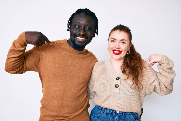 Interracial couple wearing casual clothes looking confident with smile on face, pointing oneself with fingers proud and happy.  - Фото, изображение