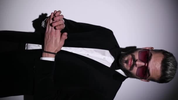függőleges portré magabiztos férfi esztergálás, rögzítése csokornyakkendő és fekete bársony szmoking, keresztbe karok és csendben gesztus szürke háttér stúdió - Felvétel, videó