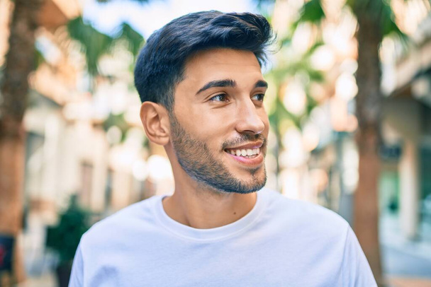 Молодий латинський чоловік посміхається щасливою прогулянкою по місту
. - Фото, зображення