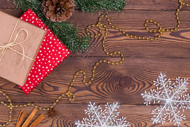 Weihnachten und Neujahr Urlaub Hintergrund. Dekor mit Geschenken, Tannenzweigen, Zapfen, Weihnachtsschmuck, Perlen, Schneeflocken, Zimtstangen auf einem Holztisch. Flacher, leerer Raum - Foto, Bild