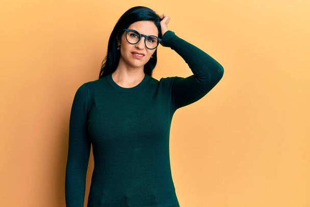 Young caucasian woman wearing casual clothes and glasses confuse and wonder about question. uncertain with doubt, thinking with hand on head. pensive concept.  - Photo, image