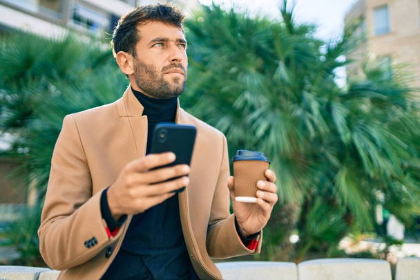 Красивий бізнесмен в елегантній куртці, використовуючи смартфон на відкритому повітрі
 - Фото, зображення