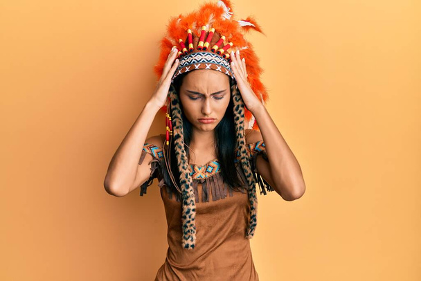 Giovane donna bruna in costume indiano che soffre di mal di testa disperato e stressato perché il dolore e l'emicrania. mani sulla testa.  - Foto, immagini