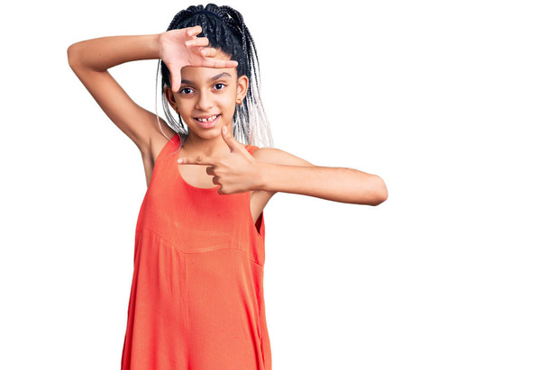 Jolie fille afro-américaine portant des vêtements décontractés souriant faisant cadre avec les mains et les doigts avec le visage heureux. concept de créativité et photographie.  - Photo, image