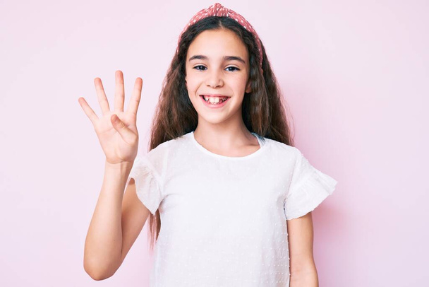 Мила дівчина з іспаномовним дитячим одягом і діадемою, показуючи і вказуючи пальцями номер чотири, посміхаючись впевнено і щасливо
.  - Фото, зображення