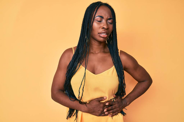 消化不良、痛みを伴う病気が体調不良のため、アフリカ系アメリカ人女性は胃の上に手でカジュアルな服を着ています。キャッシュ・コンセプト.  - 写真・画像