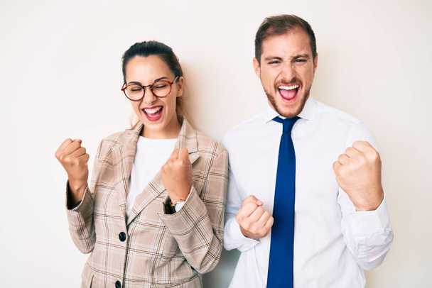 Beautiful couple wearing business clothes celebrating surprised and amazed for success with arms raised and eyes closed. winner concept.  - Foto, Bild