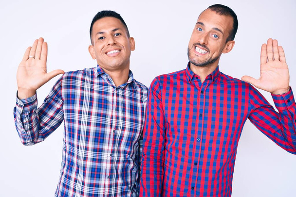 Nuori homo pari kaksi miestä päällään rento vaatteita luopumassa tervehtimään onnellinen ja hymyilevä, ystävällinen tervetullut ele  - Valokuva, kuva
