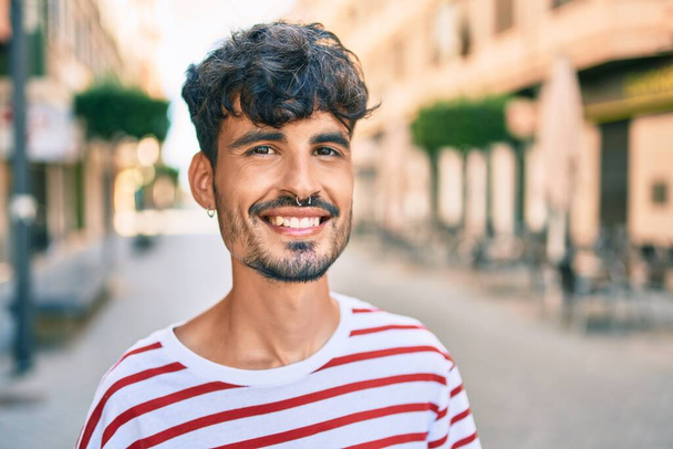 Genç İspanyol adam gülümsüyor Mutlu bir şekilde yürüyor şehrin caddesinde. - Fotoğraf, Görsel