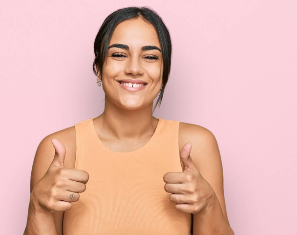 Young brunette woman wearing casual clothes success sign doing positive gesture with hand, thumbs up smiling and happy. cheerful expression and winner gesture.  - Φωτογραφία, εικόνα