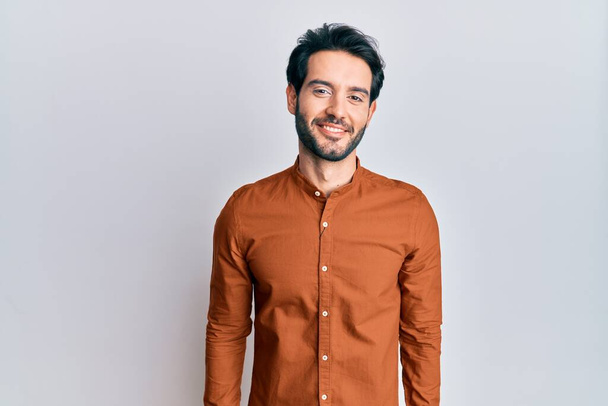 Junger hispanischer Mann in lässiger Kleidung mit einem fröhlichen und kühlen Lächeln im Gesicht. Glück gehabt.  - Foto, Bild