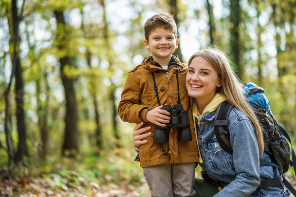 Happy mother and son are hiking in forest in autumn. - Photo, Image