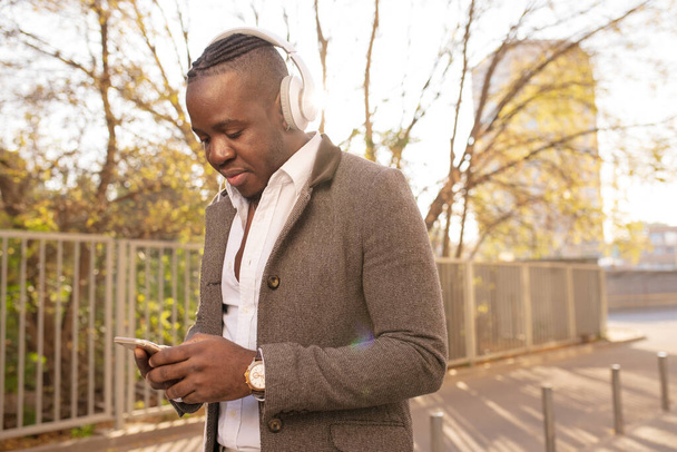 African American man listening to music with headphones on head walking in city - Fotó, kép