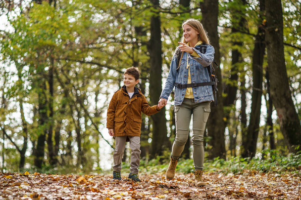 Gelukkige moeder en zoon wandelen in het bos. - Foto, afbeelding