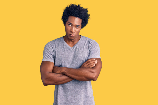 Pohledný africký Američan s afro vlasy v neformálním oblečení skeptický a nervózní, nesouhlasný výraz na tváři se zkříženýma rukama. negativní osoba.  - Fotografie, Obrázek