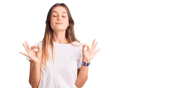 Beautiful caucasian woman wearing casual white tshirt relaxed and smiling with eyes closed doing meditation gesture with fingers. yoga concept.  - Photo, Image