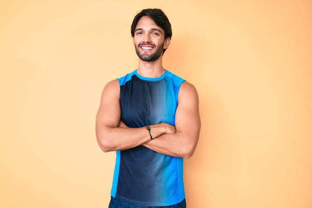 Hombre hispano guapo usando ropa deportiva cara feliz sonriendo con los brazos cruzados mirando a la cámara. persona positiva.  - Foto, Imagen