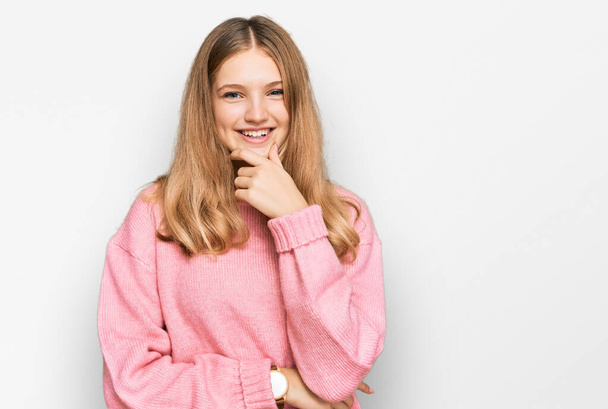 Beautiful young caucasian girl wearing casual winter sweater looking confident at the camera smiling with crossed arms and hand raised on chin. thinking positive.  - Photo, Image