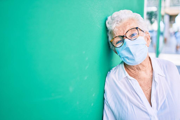 Aînée femme âgée aux cheveux gris portant un masque de sécurité contre le coronavirus à l'extérieur - Photo, image