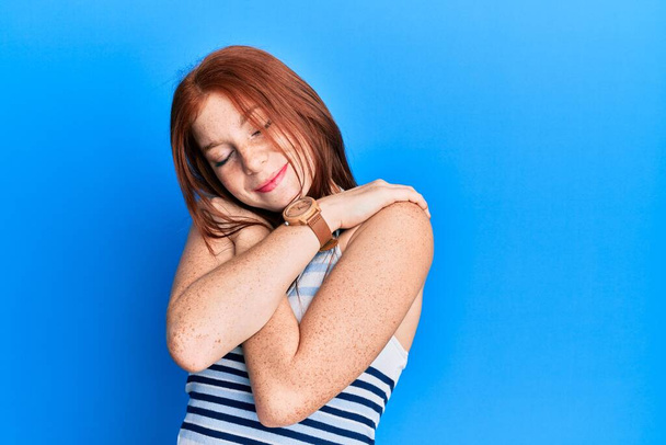 Young red head girl wearing casual clothes hugging oneself happy and positive, smiling confident. self love and self care  - Photo, Image