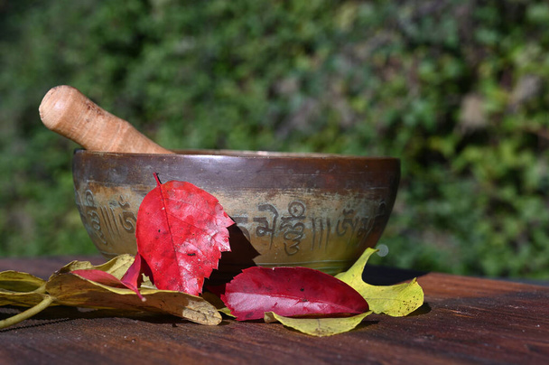 Tibetaanse zangkom. en herfstbladeren op een houten plank - Foto, afbeelding