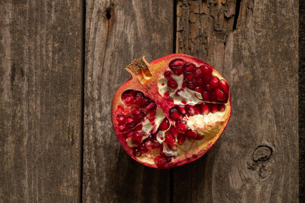 cut pomegranate lies on a wooden table close-up - Фото, зображення