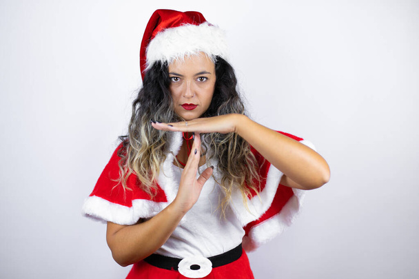 молодая красивая женщина в костюме Санта-Клауса на белом фоне делает жесты руками, разочарованное и серьезное лицо - Фото, изображение