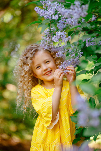 piękna mała dziewczynka pozowanie w liliowe kwiaty - Zdjęcie, obraz