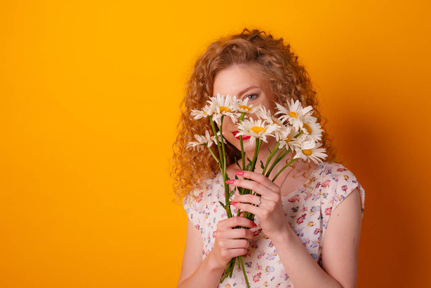 girl with a bouquet of daisies on orange background - Photo, Image