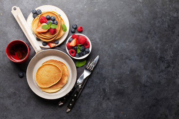 Heerlijke zelfgemaakte pannenkoeken met zomerbessen en thee als ontbijt. Bovenaanzicht met kopieerruimte - Foto, afbeelding