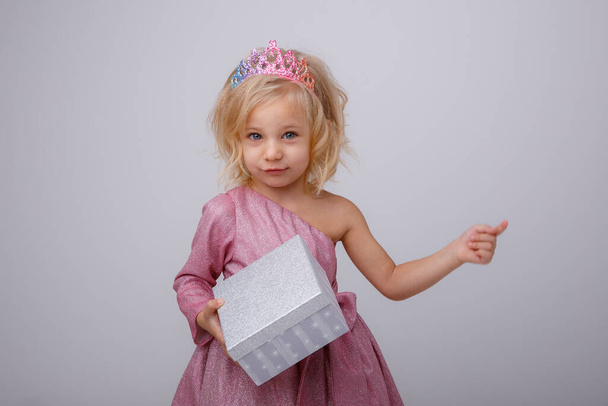 gyönyörű kislány szőke hercegnő egy ajándék a kezében  - Fotó, kép