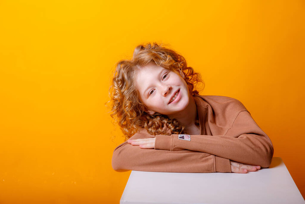 dreamy teenage girl posing against orange  - Foto, Imagen