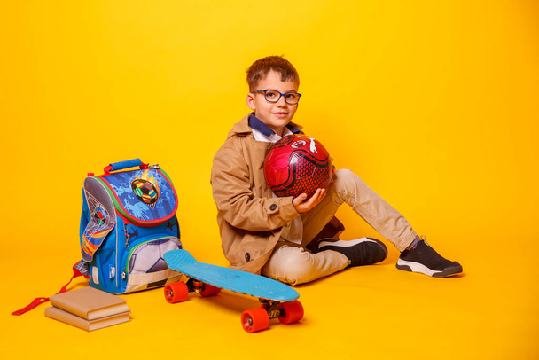 little boy with books and backpack on yellow background - Foto, Imagem