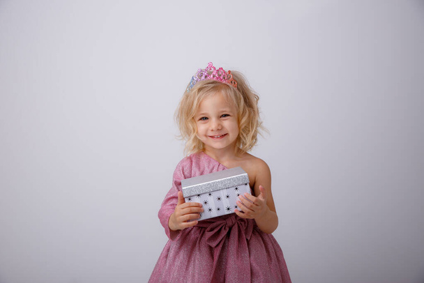 όμορφο κοριτσάκι ξανθιά πριγκίπισσα με ένα δώρο στα χέρια της  - Φωτογραφία, εικόνα