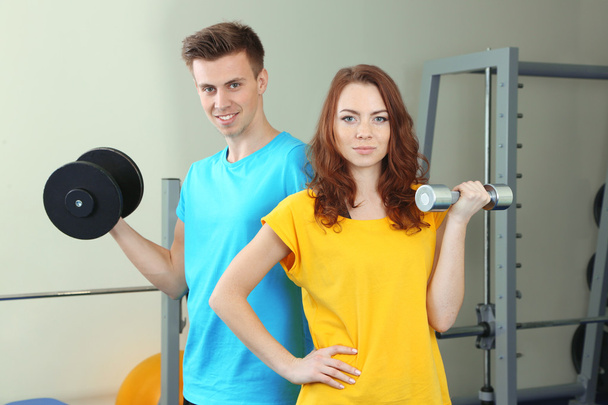 Young beautiful peoples engaged with dumbbells in gym - Fotografie, Obrázek