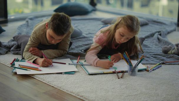 Erkek ve kız kardeş renkli kalemlerle resim çiziyor. Çocuklar evde sanat yapıyor.. - Fotoğraf, Görsel
