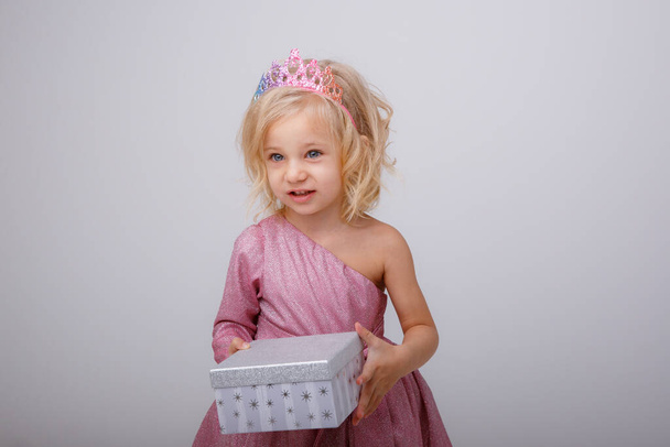 gyönyörű kislány szőke hercegnő egy ajándék a kezében  - Fotó, kép