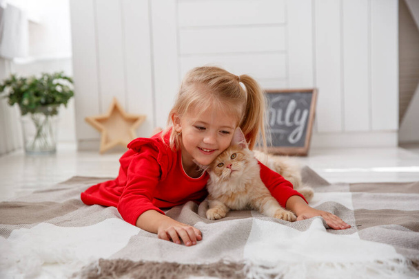 mała dziewczynka bawiąca się z maine coon kotek na podłodze - Zdjęcie, obraz