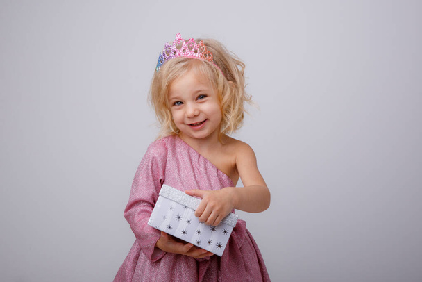 mooi klein meisje blond prinses met een geschenk in haar handen  - Foto, afbeelding