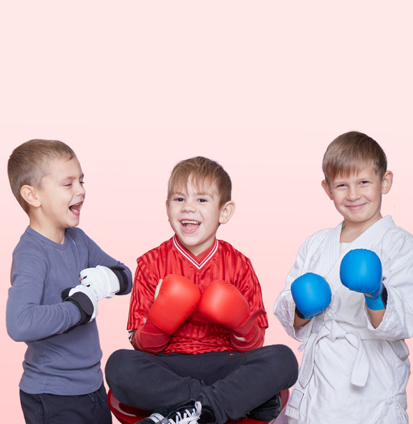 Sobre un fondo claro, tres pequeños atletas con almohadillas en las manos - Foto, Imagen