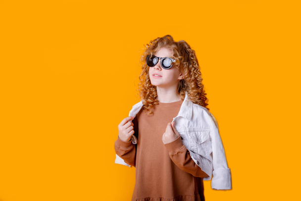 carino ragazza adolescente alla moda in posa in studio contro arancione  - Foto, immagini
