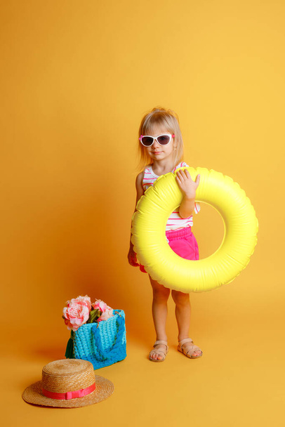 klein meisje met opblaasbare ring op roze achtergrond - Foto, afbeelding
