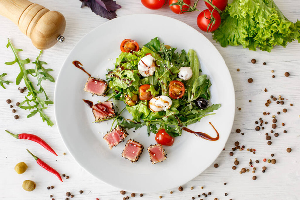 Insalata di nicoise con tonno, foglie di insalata e uovo in camicia su un piatto bianco del menu del ristorante - Foto, immagini