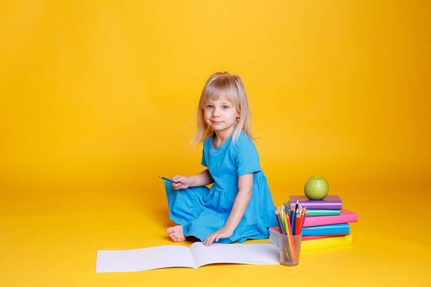 Koncepcja edukacji przedszkolnej, dziewczyna z stosem książek i jabłko na pomarańczowym tle - Zdjęcie, obraz