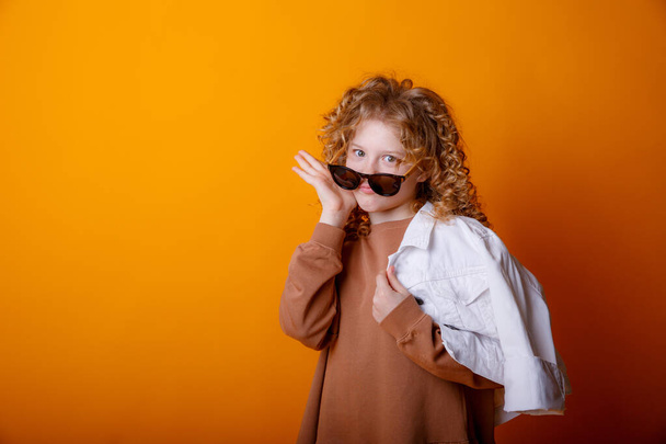cute fashionable teenage girl posing in studio against orange  - Fotografie, Obrázek